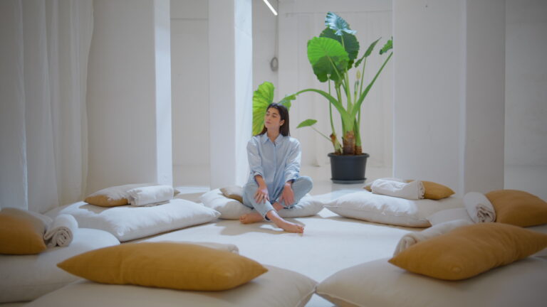 Dreamy woman relaxing alone in cozy yoga space. Peaceful manager rest after work contemplating in comfy therapy room. Beautiful serene girl enjoying tranquil moment feeling inner harmony peace of mind
